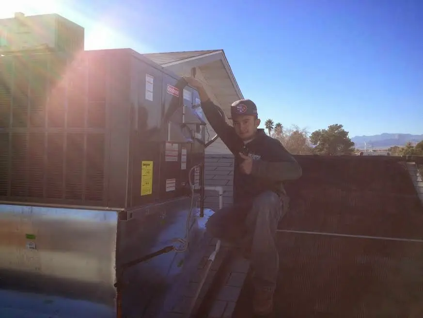 HVAC technician performing AC Tune-Up on a rooftop unit in Londonderry